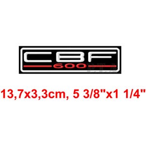 以下が含まれることがあります： 赤のアクセントが付いた長方形の白黒CBF 600ロゴ。テキスト「CBF 600」は白で表示されます。寸法は13.7cm x 3.3cmです。