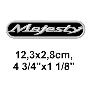 May include: A black and white embroidered patch with the word "Majesty" in a stylized font. The patch is oval-shaped and measures 4 3/4" x 1 1/8".