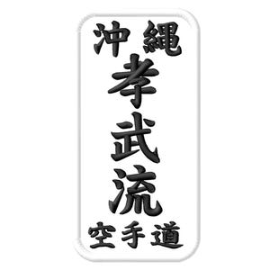 Pode incluir: Um emblema retangular branco bordado com cantos arredondados, apresentando caracteres kanji japoneses pretos dispostos verticalmente no centro, lendo Okinawa Kōbū-ryū Karate-dō, com uma borda branca espessa costurada ao redor do design.