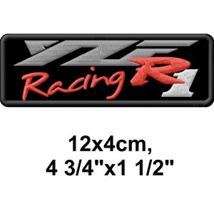 Könnte beinhalten: Eine weiße Keramik-Tasse mit schwarzem Henkel und dem Text "But First, Coffee" in fetter, schwarzer Schrift. Die Tasse steht vor einem verschwommenen Hintergrund, der eine gemütliche Umgebung suggeriert.