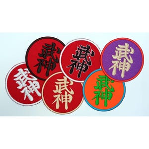 Puede incluir: Una colección de parches redondos bordados en varios colores. Cada parche presenta caracteres japoneses en un color contrastante. Los parches son rojos, naranjas, morados y blancos, con letras negras, blancas y verdes.