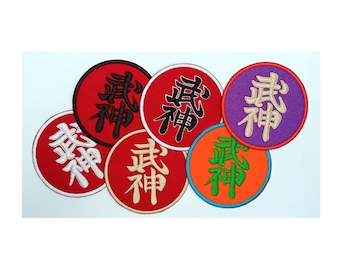 Op de afbeelding: Een verzameling ronde geborduurde patches in verschillende kleuren. Elke patch heeft Japanse karakters in een contrasterende kleur. De patches zijn rood, oranje, paars en wit, met zwarte, witte en groene letters.