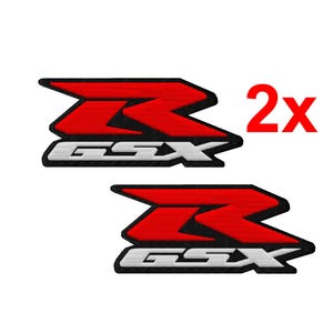 May include: Two embroidered patches featuring the Suzuki GSX logo. The logo is a stylized red 'Z' shape with a white outline, and the text 'GSX' in white. The number '2x' is in red, indicating two patches.