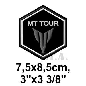 May include: Black and white embroidered patch with the text "MT TOUR" and a stylized emblem. The patch is a hexagon shape with a white border. The patch measures 3" x 3 3/8".