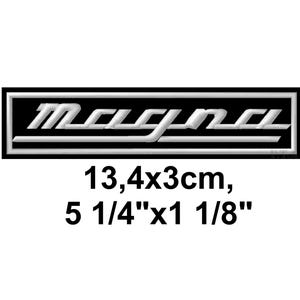 May include: A black rectangular patch with the word "Magna" in white, outlined in white. The patch measures 5 1/4" x 1 1/8".