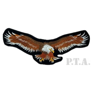 May include: Embroidered patch of a bald eagle with outstretched wings. The eagle has brown and white feathers, a yellow beak, and a black border. The text "P.T.A." is printed in grey.