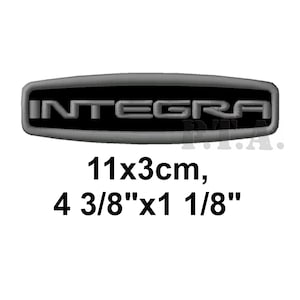 May include: A black and silver Integra emblem. The emblem is oval-shaped and features the word "INTEGRA" in silver lettering. The dimensions are 4 3/8" x 1 1/8" (11x3cm).