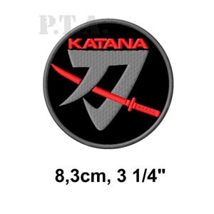 May include: Embroidered patch with a black circular background. The patch features the word "KATANA" in red above a gray stylized sword design. A red katana sword is diagonally across the design. The patch is 3 1/4 inches in diameter.