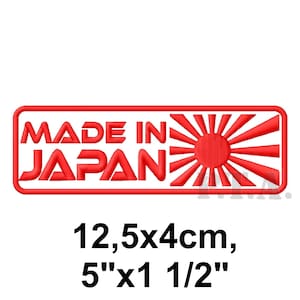 Peut inclure: Un écusson rectangulaire rouge avec le texte "MADE IN JAPAN" en lettres blanches en gras. Le design comprend un emblème de soleil levant. L'écusson mesure 12,5 cm x 4 cm.