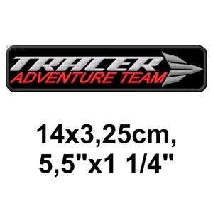 May include: Black rectangular patch with the words "TRAILER ADVENTURE TEAM" in white and red. A white arrow points right. The patch measures 5.5" x 1 1/4" (14 x 3.25 cm).