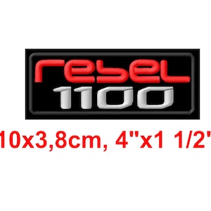May include: Embroidered patch featuring the word "rebel" in red and "1100" in white on a black rectangular background. The patch measures 10cm x 3.8cm.