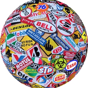 May include: A spherical object covered in a collage of embroidered patches. The patches feature various brand logos and text, including "BELL HELMETS", "MOTUL", "MICHELIN", and "76". The patches are in various colors, including red, white, blue, and yellow.