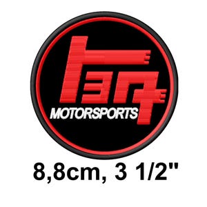 May include: A white ceramic mug with a black handle and the text "But First, Coffee" in a bold, black font. The mug is set against a blurred background, suggesting a cozy setting.