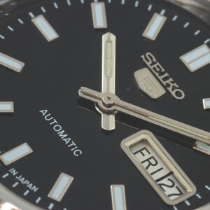 May include: Close-up of a Seiko automatic wristwatch with a black dial. The watch face features silver hands and markers, with the day and date displayed. The text "SEIKO", "AUTOMATIC", "MADE IN JAPAN", and "FRI 27" are visible.