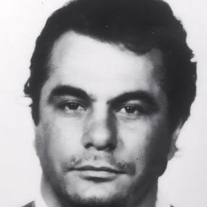 May include: Black and white mugshot of a man with short dark hair. He is looking directly at the camera with a serious expression.