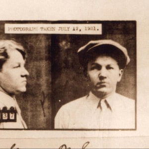 May include: Black and white mugshot of two men taken on July 17, 1981. Both men are looking at the camera. The man on the left has short dark hair and is wearing a white shirt. The man on the right has short dark hair and is wearing a white shirt and a dark cap.