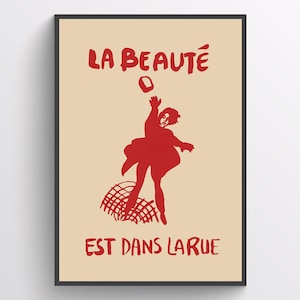 May include: A red and white poster with the text "LA BEAUTÉ EST DANS LA RUE" and a red silhouette of a person throwing a brick.