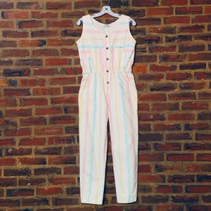May include: A white striped jumpsuit with pink, blue, and yellow stripes. The jumpsuit has a button closure and pockets.