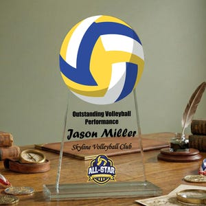 Peut inclure: Un trophée en acrylique transparent avec un design de ballon de volley-ball jaune, blanc et bleu. Le trophée indique « Performance exceptionnelle au volley-ball » et comprend le nom « Jason Miller » et « Skyline Volleyball Club ».