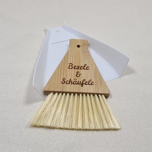 Könnte beinhalten: Ein Besen- und Schaufelset aus Holz mit einem Bambusgriff. Der Griff ist mit dem Text "Beseele & Schäufele" graviert.