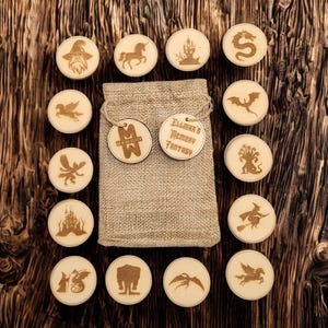 Peut inclure: Jeu de mémoire en bois avec des images gravées sur le thème de la fantaisie, comprenant un magicien, une licorne et un dragon. L'ensemble comprend un sac en tissu et des étiquettes avec le texte "Memory" et "Illmar's Memory Fantasy". Les pièces sont disposées sur une surface en bois foncé.