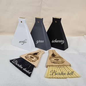 Könnte beinhalten: Drei dreieckige Vasen in Weiß, Grau und Schwarz mit Holzaufsätzen. Darunter zwei Holzschaufeln mit eingravierten Hochzeitsautodesigns und dem Text "Just Married". Eine Schaufel hat schwarze Borsten, die andere helle Borsten.