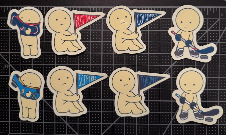 May include: A set of eight die-cut stickers featuring cartoon figures in various poses. Some figures hold pennants labeled Blue Jackets, Columbus, Sceptres, or Toronto, while others wear jerseys or hold hockey sticks with pucks on a black grid mat.