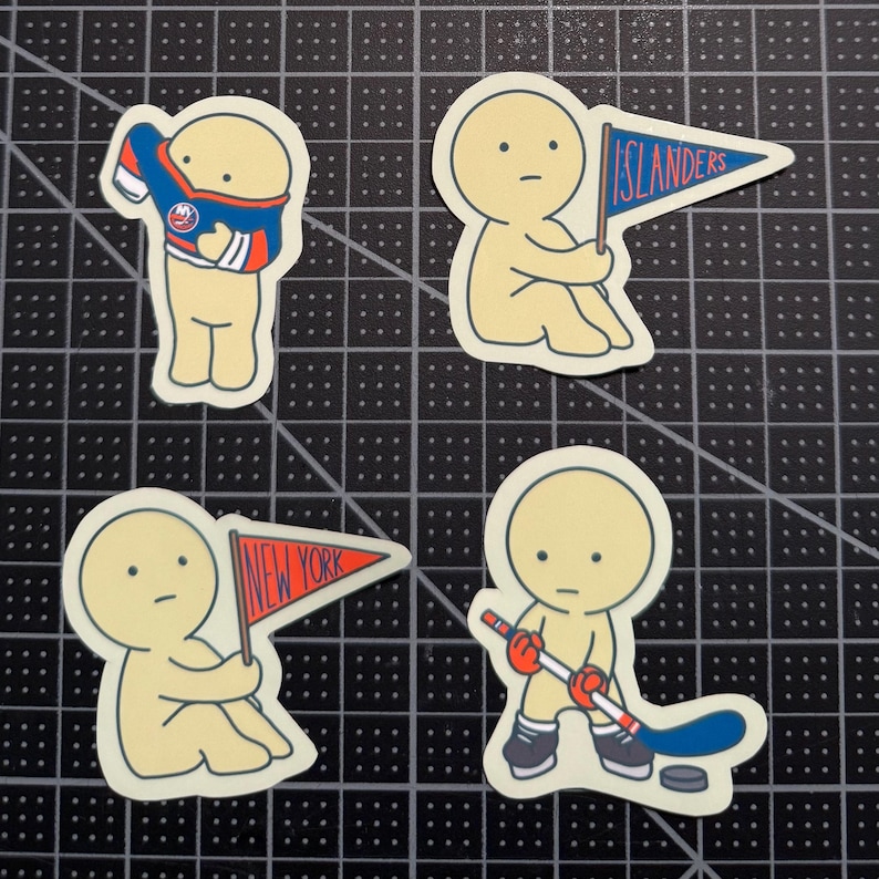 May include: Four die-cut stickers featuring a pale yellow cartoon character. One pulls on a blue and orange hockey jersey, one holds a blue pennant with the text ISLANDERS, one holds a red pennant with the text NEW YORK, and one holds a hockey stick.