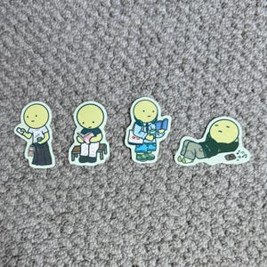 Puede incluir: Conjunto de cuatro pegatinas con figuras de dibujos animados en varias poses. Una figura sostiene una taza y un animal pequeño, otra lee un libro en un banco, una tercera sostiene un libro y una bolsa, y la última se relaja.