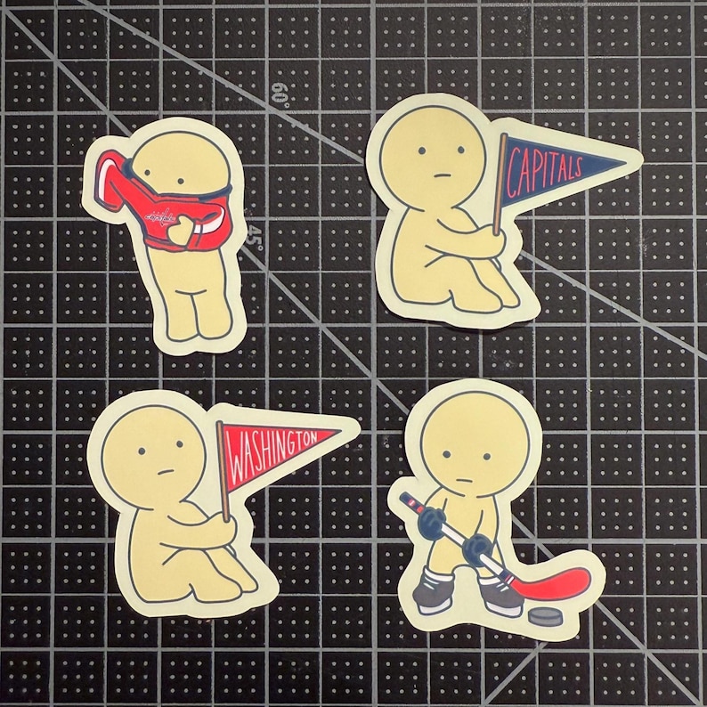 May include: Four die-cut stickers featuring a pale yellow character. One holds a red jersey, one holds a blue pennant with the text CAPITALS, one holds a red pennant with the text WASHINGTON, and one holds a hockey stick with a puck.