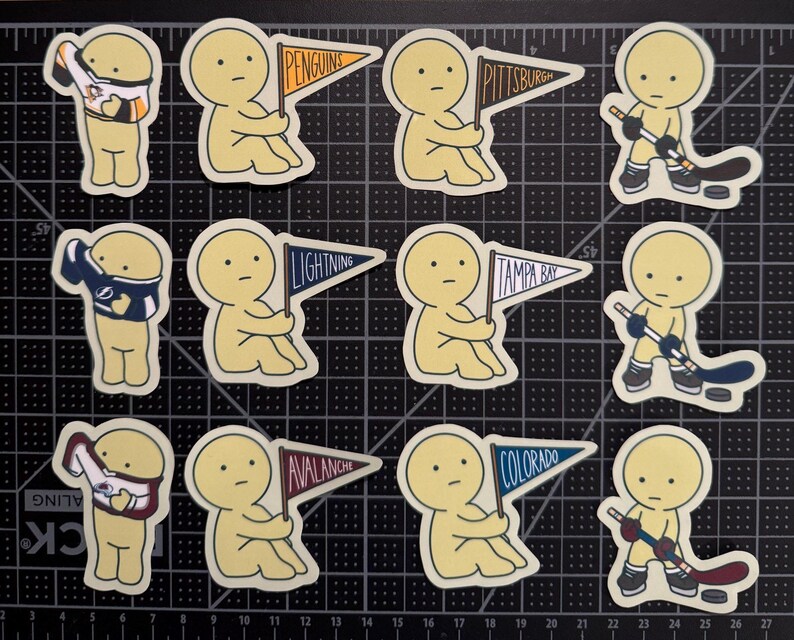 May include: A collection of twelve die-cut stickers featuring a pale yellow cartoon character in various hockey-themed poses, including wearing jerseys, holding pennants labeled Penguins, Pittsburgh, Lightning, Tampa Bay, Avalanche, and Colorado.