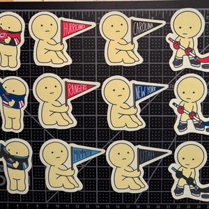 May include: A collection of twelve die-cut stickers featuring pale yellow cartoon figures. Some figures hold pennants labeled Hurricanes, Carolina, Rangers, New York, Mammoth, and Utah. Others wear sports jerseys or hold hockey sticks with pucks.