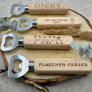 Könnte beinhalten: Vier Holz-Flaschenöffner mit verschiedenen gravierten Botschaften. Die Botschaften lauten "Opa ist der Beste", "Papa ist der Beste", "Onkel ist der Beste" und "Flaschenöffner".