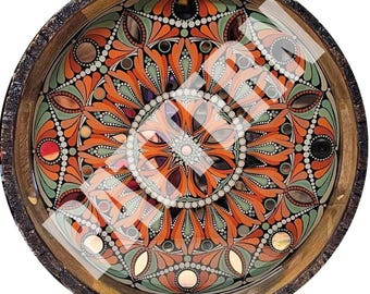 May include: A round wooden tray with a decorative mandala design painted in orange, green, and white. The mandala features a repeating pattern of circles, dots, and leaves.