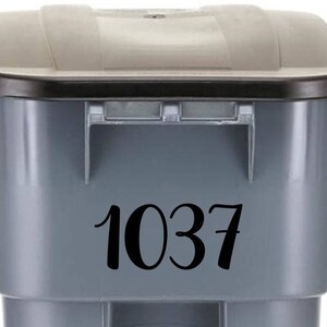 May include: Gray trash can with a black lid and a black number 1037 sticker on the front.
