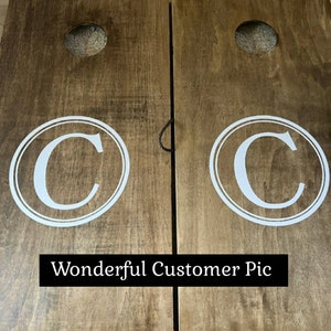 Op de afbeelding: Twee houten cornhole-borden met een witte cirkel en de letter "C" in het midden van elk bord. De borden zijn bruin en hebben een natuurlijke houten afwerking. De tekst "Wonderful Customer Pic" staat onderaan de afbeelding.
