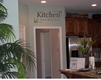 May include: A kitchen with a sign that reads "Kitchen - the heart of the home". The kitchen has a stainless steel fridge, wooden cabinets, and a granite worktop.