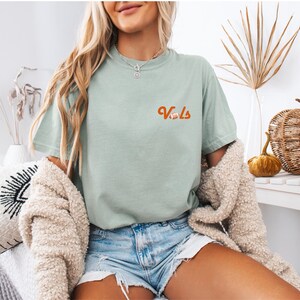 May include: A light green t-shirt with the word "Vols" in orange lettering and a small football graphic.