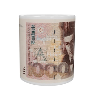 Puede incluir: Taza de cerámica blanca con un diseño de un billete alemán de 1000 marcos alemanes. La taza muestra el retrato, los elementos arquitectónicos y el texto del billete. La taza es cilíndrica y tiene un interior blanco.