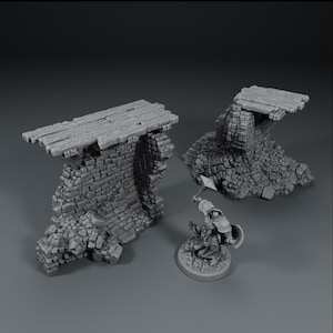 Könnte beinhalten: Miniatur-Geländeteile für Tabletop-Spiele. Das Bild zeigt zwei verwitterte Steinruinen mit Holzplanken und eine Miniaturfigur eines Kriegers mit Hammer und Schild. Die Teile sind grau und scheinen aus Kunstharz zu sein.