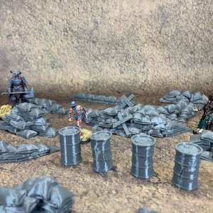 May include: A miniature war scene featuring gray sandbags, barrels, and figures on a textured surface. The scene includes several small figures, sandbags, and barrels. The figures are painted with detailed armor and are set in a war-like environment.