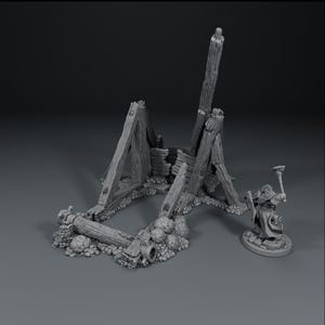 May include: A miniature, grayscale model of a dilapidated wooden structure, possibly a siege engine or building, with broken beams and a small figure holding a weapon. The model is set against a neutral background.