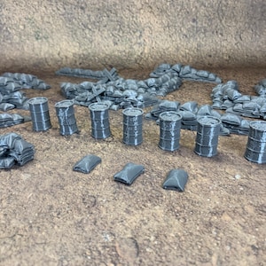 May include: Miniature grey terrain pieces for tabletop gaming, including sandbags, barrels, and small rectangular objects. The pieces are arranged on a textured brown surface. These items are designed for miniature wargaming.