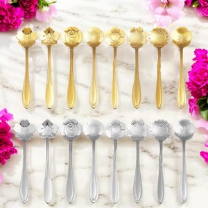 May include: A collection of decorative spoons with floral designs. The spoons are arranged in two rows, with gold-colored spoons on top and silver-colored spoons below. Each spoon features a different flower design on the bowl.