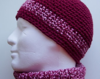 May include: A burgundy crocheted beanie with a white stripe detail. The beanie is worn on a white mannequin head.