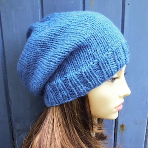 May include: A blue knitted beanie hat with a slouchy fit. The hat is made of a soft, textured yarn.
