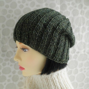 Puede incluir: Un gorro de punto verde oscuro con un ajuste holgado. El gorro tiene una textura sutilmente moteada.