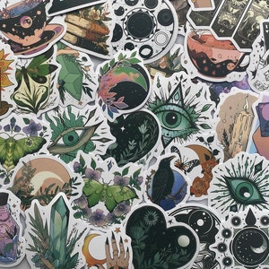 Peut inclure: Un ensemble d'autocollants variés sur des thèmes mystiques et célestes. Les motifs incluent des bougies, des yeux, des mains, des lunes, des cartes de tarot et des éléments floraux. Les autocollants présentent une variété de couleurs, avec des détails complexes.