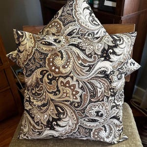 May include: A decorative throw pillow with a paisley pattern in shades of brown, black, and white.