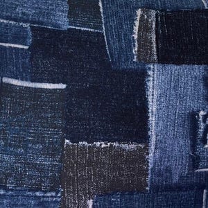 May include: Close-up of a patchwork denim fabric. The design features various shades of blue denim, including light, medium, and dark washes, arranged in a geometric pattern. The edges of the denim pieces have a frayed appearance, adding texture.